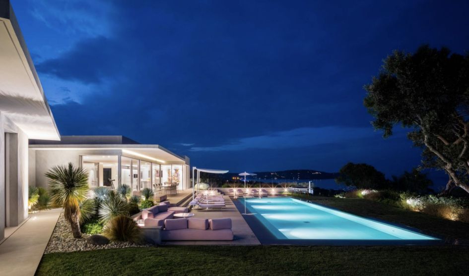 The pool terrace area of Villa Ama in at night time, with views over St Tropez behind