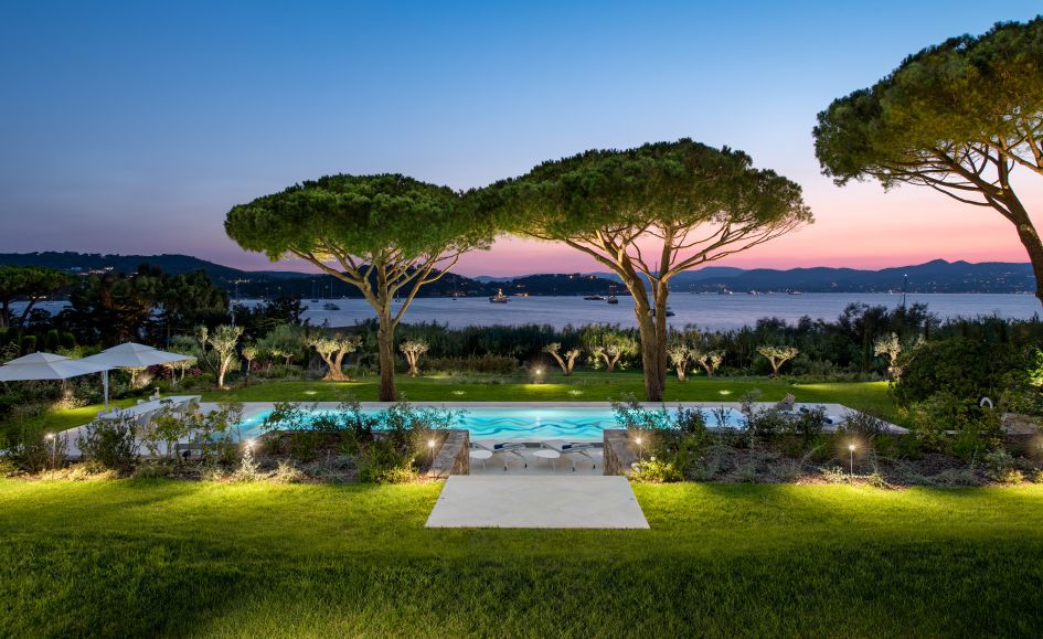 View of the garden and outdoor swimming pool of Villa Canoubwest in St Tropez, at dusk