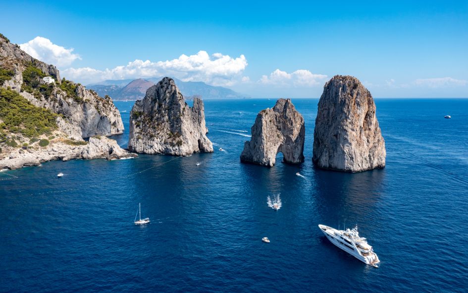 Aerial view over the Faraglioni rock formations of Capri, with yacths and sailing boats.