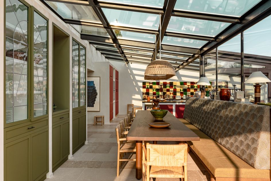 The kitchen & dining area in the glass conservatory in Les Hauts de Gordes, which implements vibrant patterned tiling and local artwork to great effect.