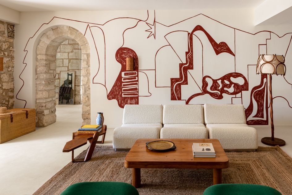 L'Étoile des Baux is one of the most unique Provence luxury villas, seen here in the main lounge of the property, a creative wall mural juxtaposes with the natural stonework of the other walls and doorway.