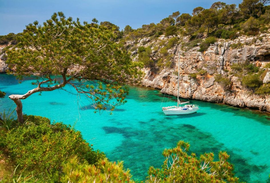 Mallorca. Credit: Consell de Mallorca Boat on clear turquoise waters in Mallorca, with trees and cliff surrounding it to showcase this truly scenic destination.