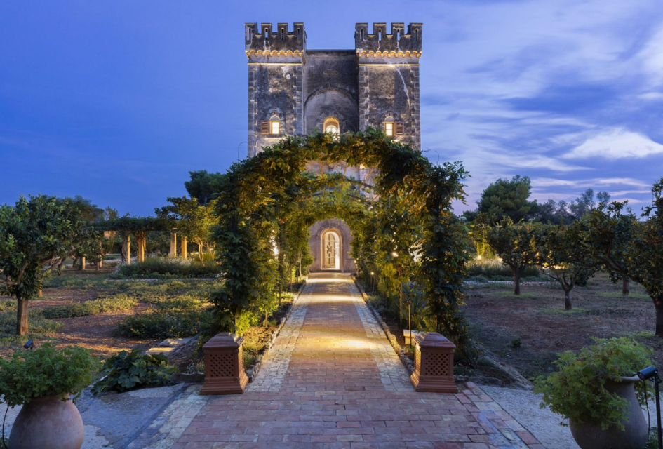Le Grand Jardin, Cannes, France Entrance to the fortress that forms the main residence building of the unique luxury villa Le Grand Jardin, Cannes. With foliage archway leading up to it and lights shiningf romt he interior at dusk.