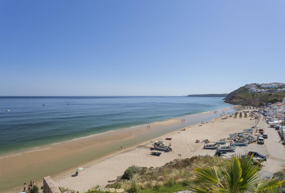 View of Salema Beach from Villa Alegria View of family friendly beach in the Algarve (Salema beach) from Villa Alegria showing a stretch of golden sand with buildings and boats in view, a great place to visit on your luxury summer holidays.