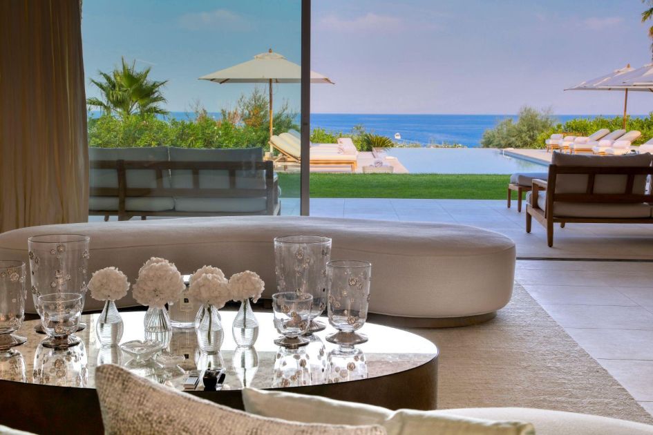 A scenic shot of the pool and sea view beyond the terrace and interiors of this luxury villa in St Tropez.