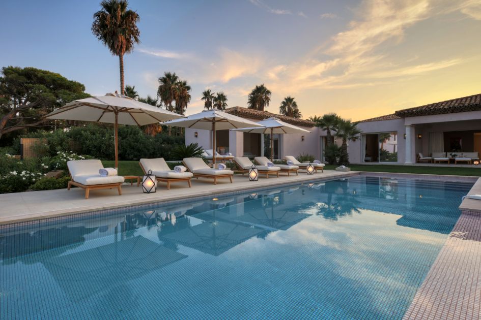 Villa Las Brisas' swimming pool and loungers under dusk, exuding a luxury ambience from afternoon to evening.