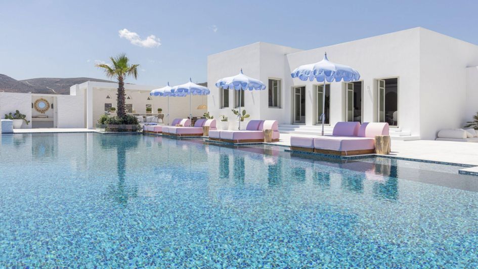 Villa Naima's outdoor pool, shaded loungers and traditional white architecture depicts a quintessential Paros backdrop for a relaxing holiday in Greece.