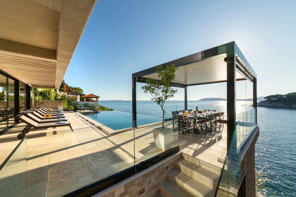 Villa L'Essenza di Dubrovnik, Dalmatian Coast The pool terrace with inifnity swimming pool, sun loungers and alfresco dining table at luxury villa rental L'Essenza di Dubrovnik. Panoramic views of the Dalmatian Coast and Adriatic behind.