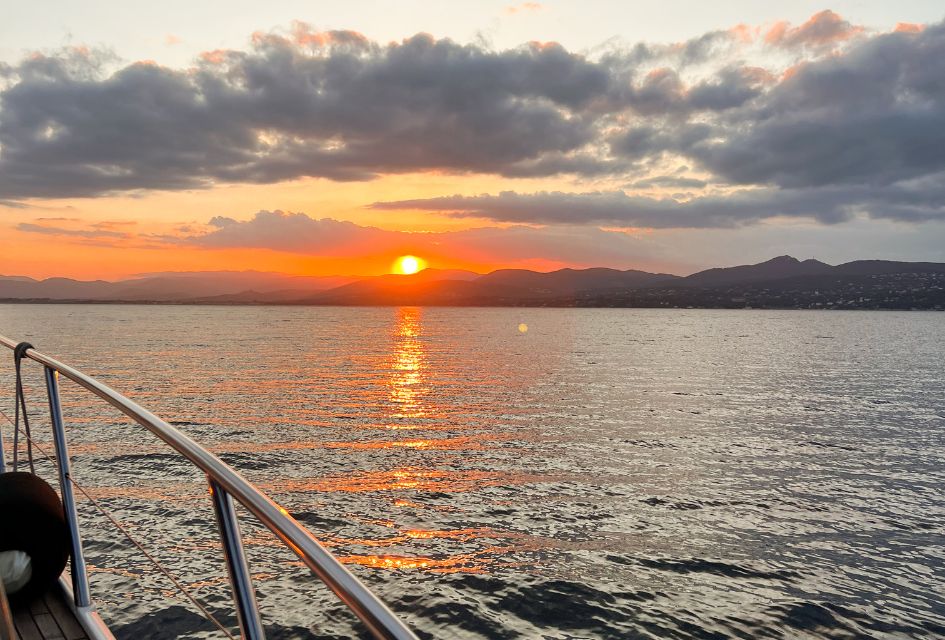 Yacht Charters in St Tropez Yacht charter in St Tropez, pictured from the side of the boat looking towards a golden sunset over the mountains in the horizon.