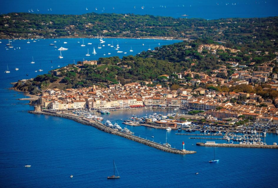 Marina of St Tropez, with yachts surrounding in teh ocean and sun shining.